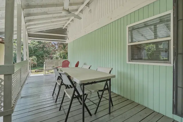 Covered porch with dining table, ceiling fan, and peaceful garden views at Fruit Tree Home
