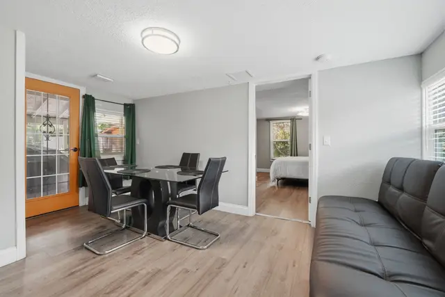 Bright modern dining area with futon, bedroom access, and patio door at Fruit Tree Home