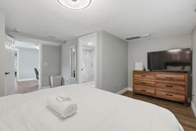 Bright modern bedroom with TV, dresser, and easy bathroom access at Fruit Tree Home
