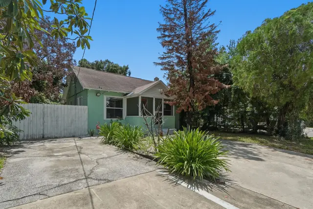 Charming green cottage with private drive, porch, and lush front yard at Fruit Tree Home