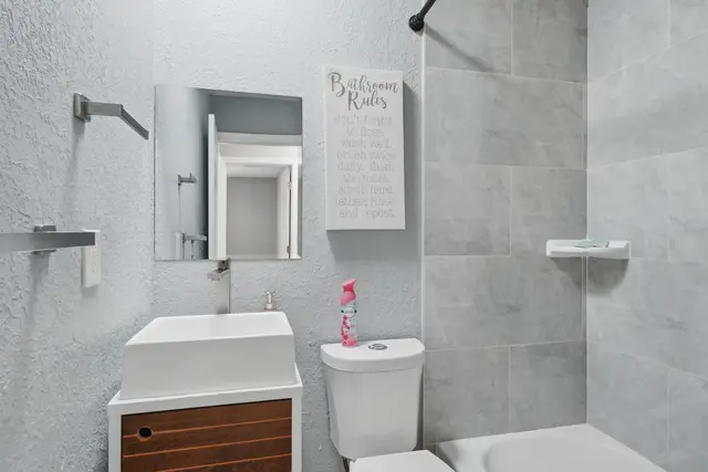 Bright modern bathroom with stylish vanity and tiled tub-shower at Fruit Tree Home