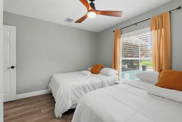 Bright twin bedroom with pool views, natural light, and fresh modern style at Fruit Tree Home