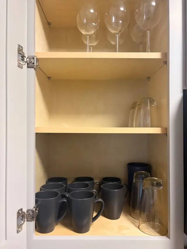 Well-stocked kitchen cabinet with mugs, glasses, and wine stemware at Amelia’s Arena Retreat