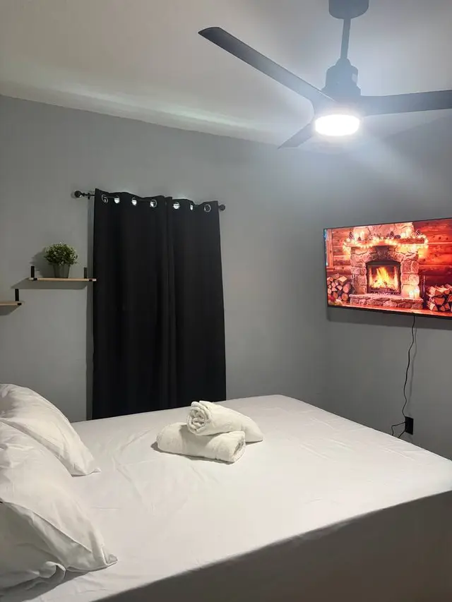 Cozy modern bedroom with blackout curtains, TV, and fresh linens at Amelia’s Arena Retreat