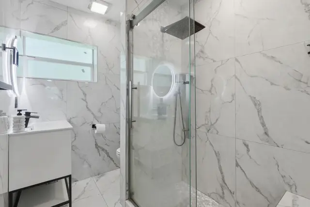 Sleek marble bath with glass walk-in shower and rainfall head at Amelia’s Arena Retreat