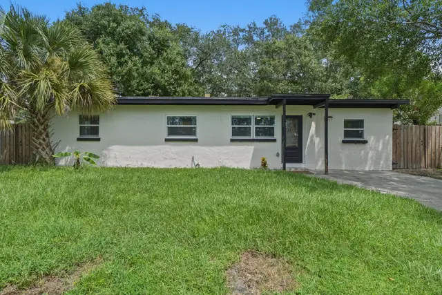 Charming modern exterior with lush lawn, palm tree, and private entry at Amelia’s Arena Retreat