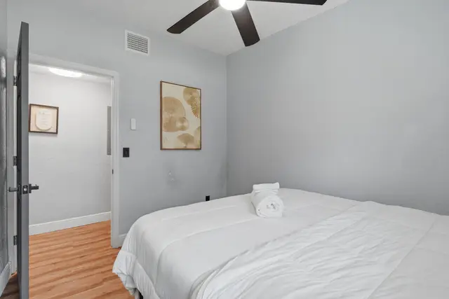 Bright minimalist bedroom with crisp linens and ceiling fan comfort at Amelia’s Arena Retreat