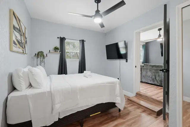 Bright, modern bedroom with TV, ceiling fan, and crisp cozy linens at Amelia’s Arena Retreat