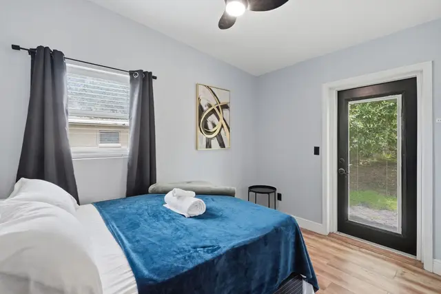Bright, cozy bedroom with outdoor access and a plush blue accent throw at Amelia’s Arena Retreat
