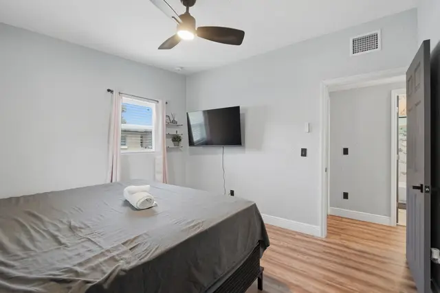 Bright, modern bedroom with wall-mounted TV and cozy minimalist style at Amelia’s Arena Retreat