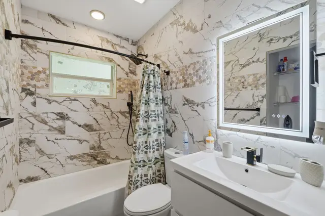Modern marble-look bathroom with tub, LED mirror, and sleek finishes at Amelia’s Arena Retreat