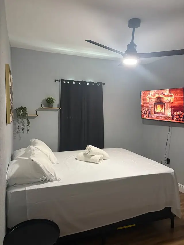 Cozy modern bedroom with TV, blackout curtains, and fresh linens at Amelia’s Arena Retreat