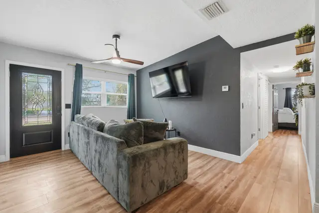 Cozy modern living room with accent wall, sectional, and large TV at Amelia’s Arena Retreat