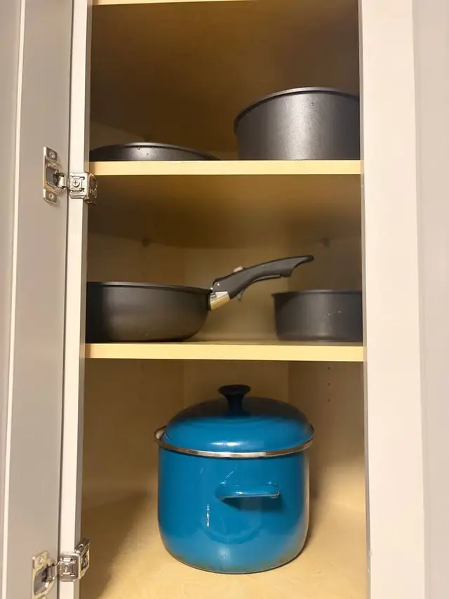 Well-stocked kitchen cabinet with pots and pans for easy home cooking at Amelia’s Arena Retreat