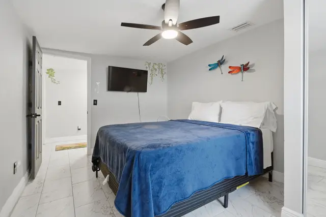 Cozy modern bedroom with TV, ceiling fan, and plush blue bedding at Piedmont