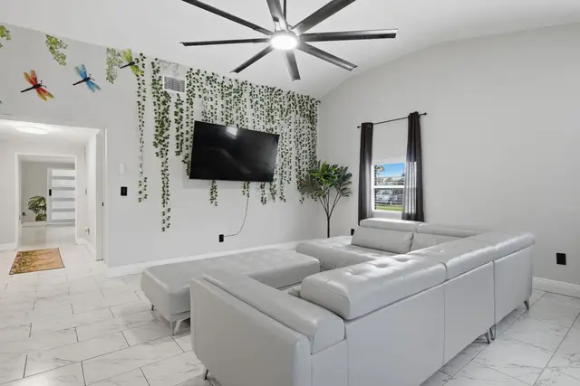 Bright modern lounge with high ceilings, big TV, and stylish white sectional at Piedmont