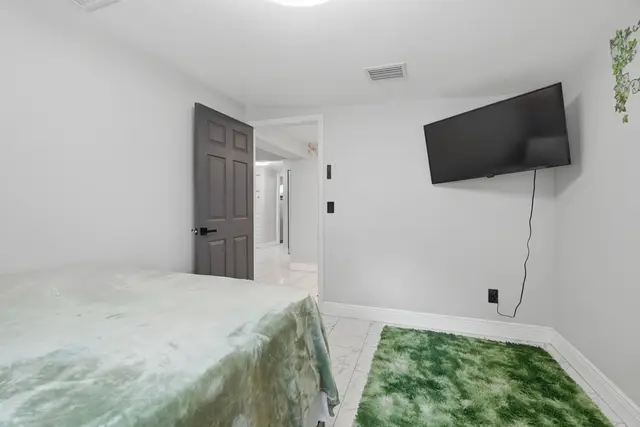 Minimalist bedroom with wall-mounted TV and soft green accents at Piedmont
