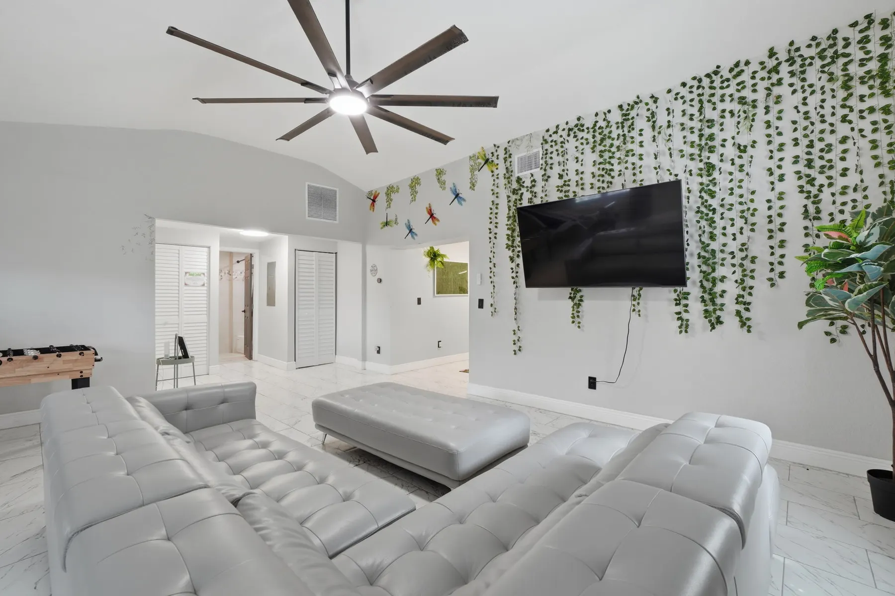 Bright modern lounge with oversized sectional, big TV, and chic greenery wall at Piedmont, a Libema home in Orlando