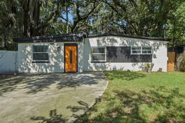 Charming modern exterior with driveway, lawn, and shady mature trees at Game Day Getaway-Downtown Orlando