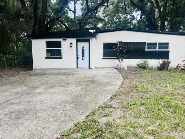 Modern black-and-white bungalow with ample parking beneath shady oaks. at Game Day Getaway-Downtown Orlando