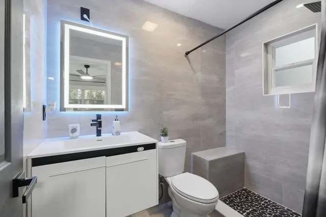 Modern spa-style bathroom with LED mirror, walk-in shower, and sleek finishes at Game Day Getaway-Downtown Orlando