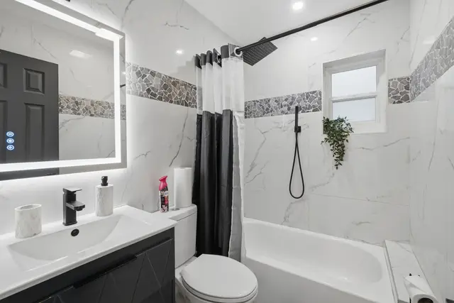 Modern spa-like bathroom with tub, rainfall shower, and sleek finishes at Game Day Getaway-Downtown Orlando