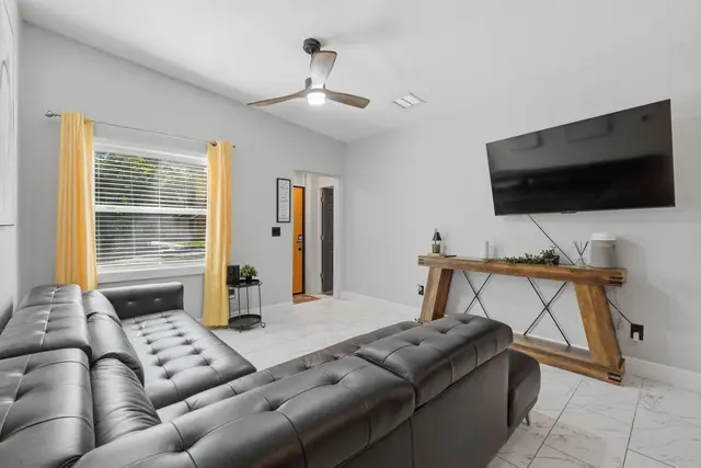 Bright modern living room with large sectional and wall-mounted TV at Game Day Getaway-Downtown Orlando