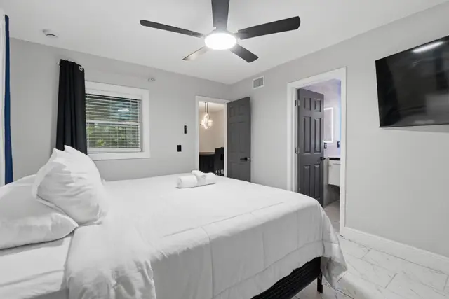Bright modern bedroom with TV, ceiling fan, and ensuite bath access at Game Day Getaway-Downtown Orlando