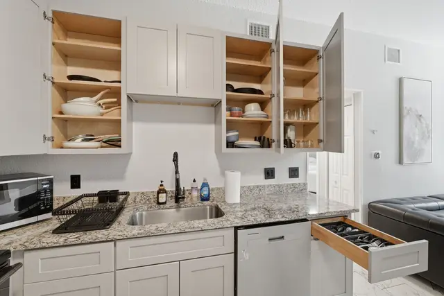 Well-stocked modern kitchen with granite counters and organized storage at Game Day Getaway-Downtown Orlando