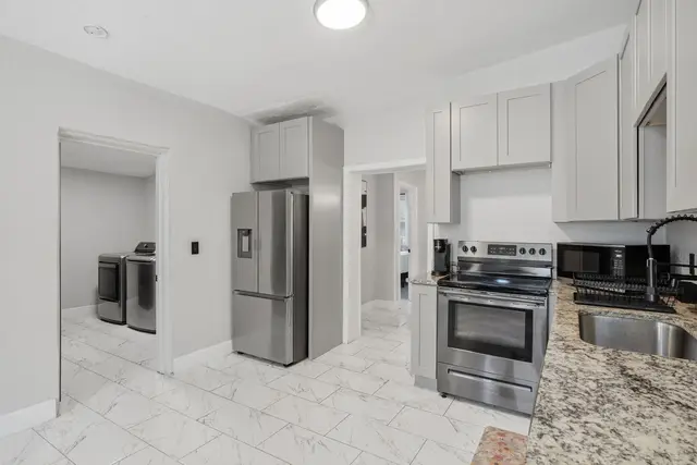 Bright modern kitchen with granite counters, stainless appliances & laundry access at Game Day Getaway-Downtown Orlando