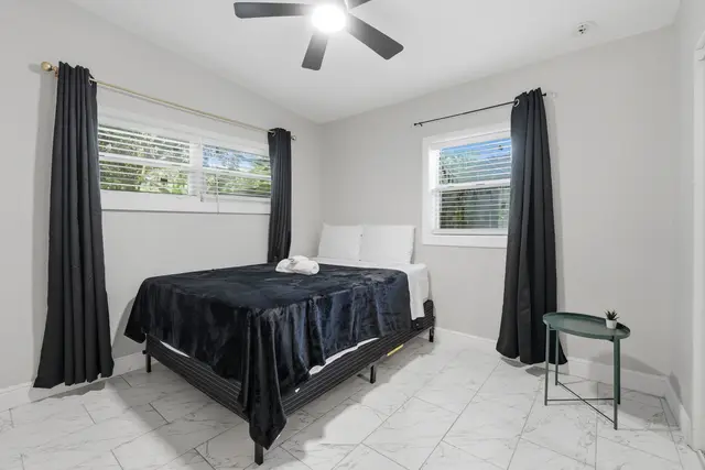 Bright modern bedroom with blackout curtains and sleek tile floors at Game Day Getaway-Downtown Orlando