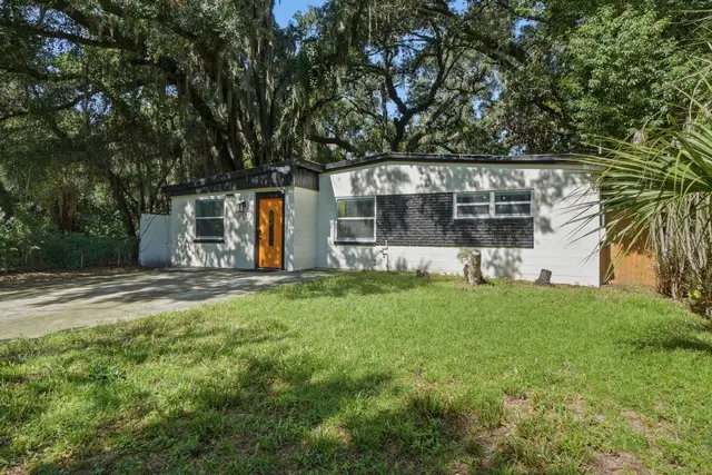 Modern single-story home with spacious lawn and peaceful tree-lined setting at Game Day Getaway-Downtown Orlando