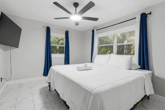 Bright modern bedroom with king bed, TV, and sunny corner windows at Game Day Getaway-Downtown Orlando
