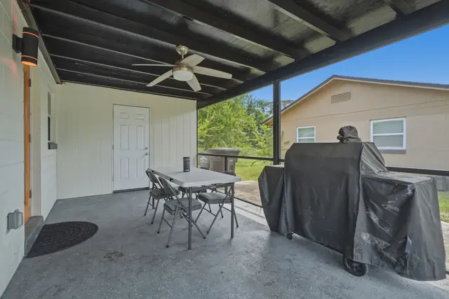 Covered patio with grill, ceiling fan, and outdoor dining space at WinterPark Home