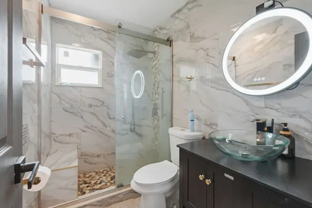 Modern spa-style bathroom with glass shower and LED mirror at WinterPark Home