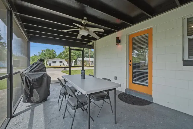 Screened-in patio with outdoor dining, grill, and ceiling fan at WinterPark Home