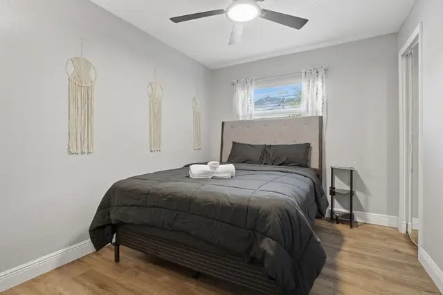 Cozy minimalist bedroom with plush bed, wood floors, and natural light at WinterPark Home