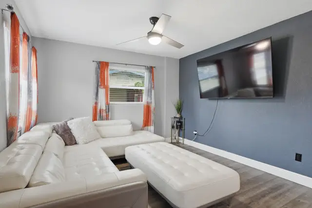 Modern lounge with oversized sectional, ottoman, and large wall-mounted TV at WinterPark Home