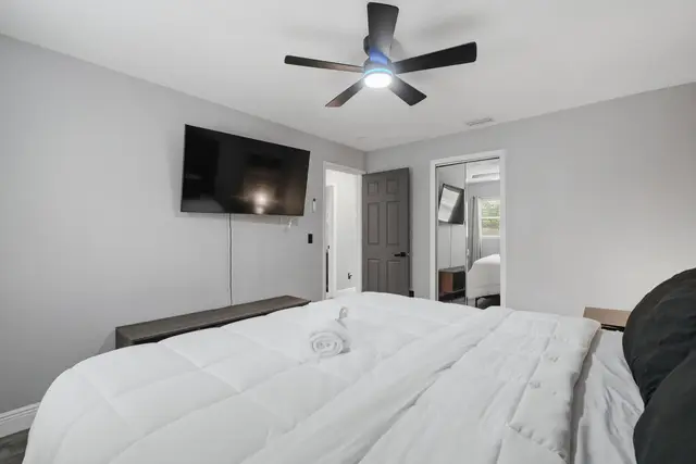Bright modern bedroom with TV, mirrored closet, and cozy bedding at WinterPark Home