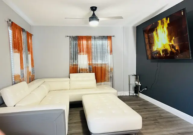 Bright modern living room with sectional, big TV, and natural light at WinterPark Home