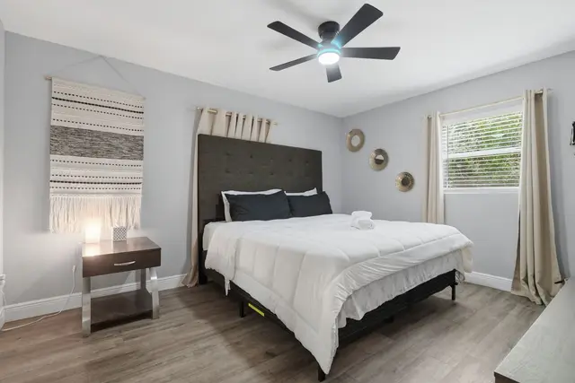 Bright modern bedroom with plush bedding, natural light, and a ceiling fan at WinterPark Home