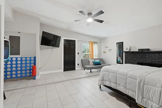Bright modern bedroom with TV, seating area, and stylish fireplace at The Clue House