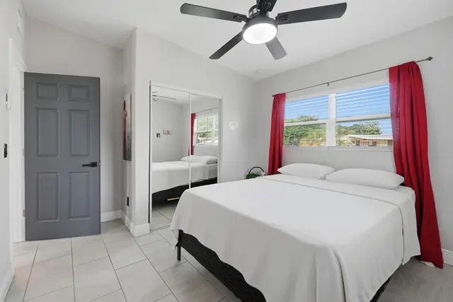Bright, modern bedroom with natural light, mirrored closet, and ceiling fan at The Clue House