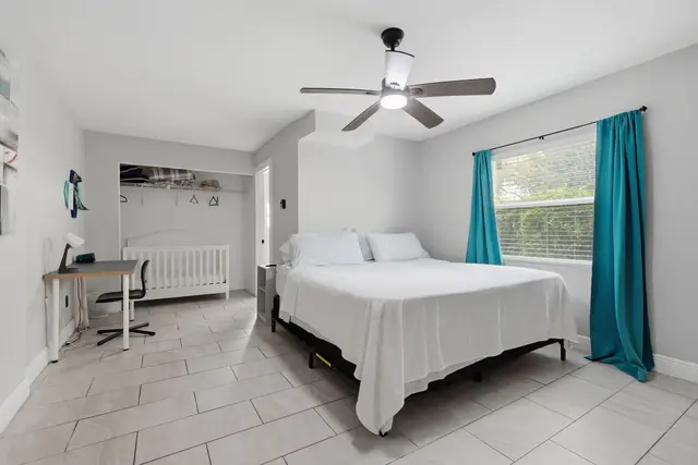 Bright family-friendly bedroom with crib, desk, and natural light at The Clue House