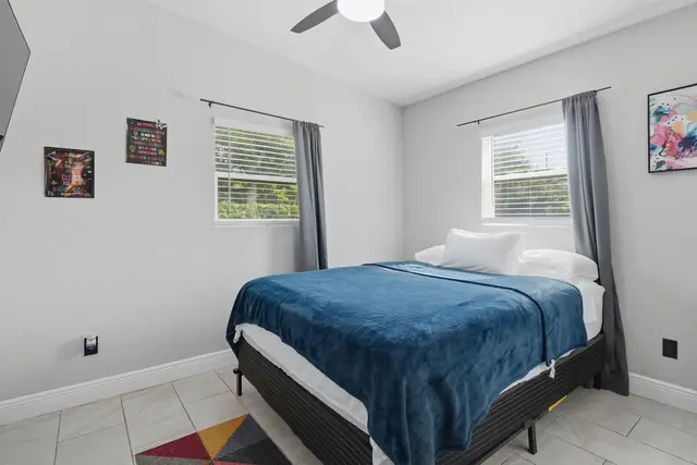 Bright, cozy bedroom with natural light and a plush blue accent bed at The Clue House