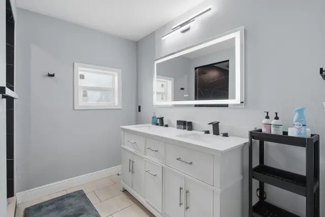 Modern double vanity bathroom with backlit mirror and sleek finishes at The Clue House