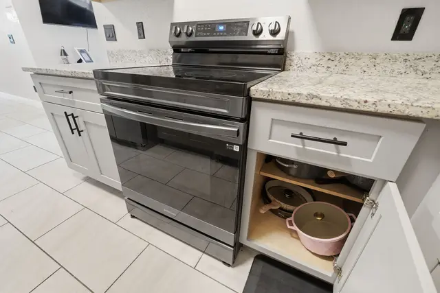 Modern kitchen with stainless range, granite counters, and stocked cookware at The Clue House