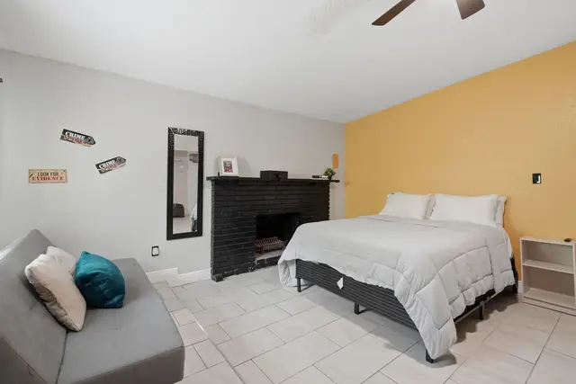 Cozy bedroom with queen bed, fireplace, and stylish accent wall at The Clue House