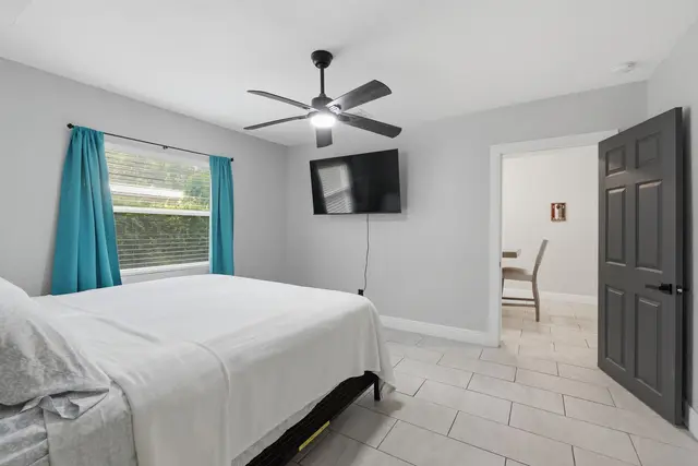 Bright, airy bedroom with TV, ceiling fan, and stylish modern finishes at The Clue House
