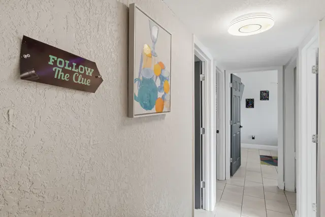 Bright hallway with playful decor, modern lighting, and clean tiled floors at The Clue House